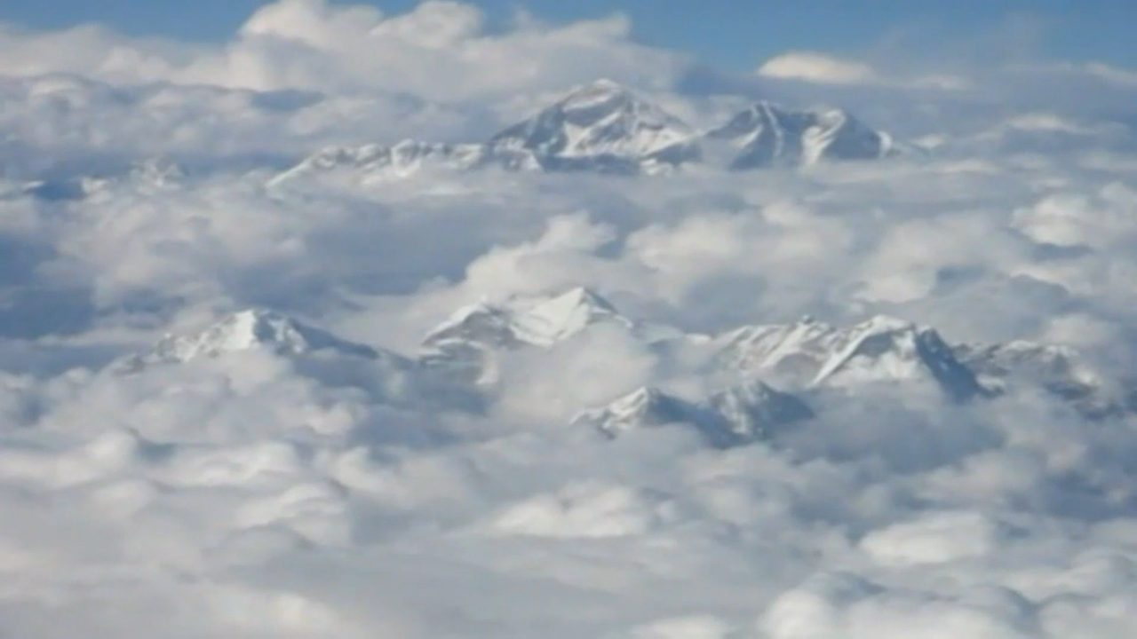 The Everest massif standing above a cloud deck, seen from an aircraft.
